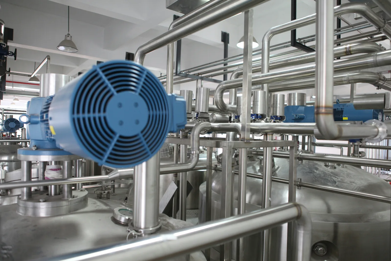 Blue electric motor beside industrial pipes