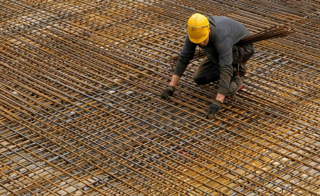 Worker fastening a steel reinforcement grid